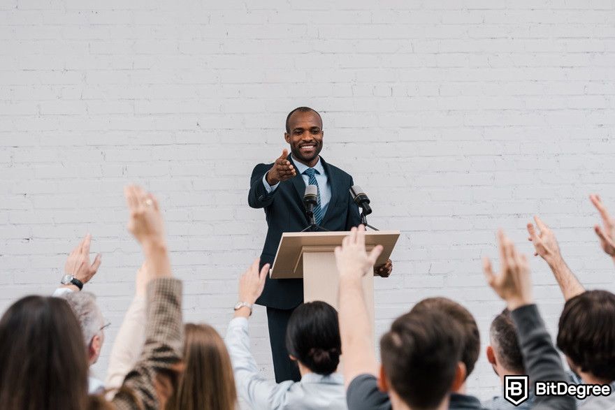 Blockchain education: Back view of journalists in front of a politician.