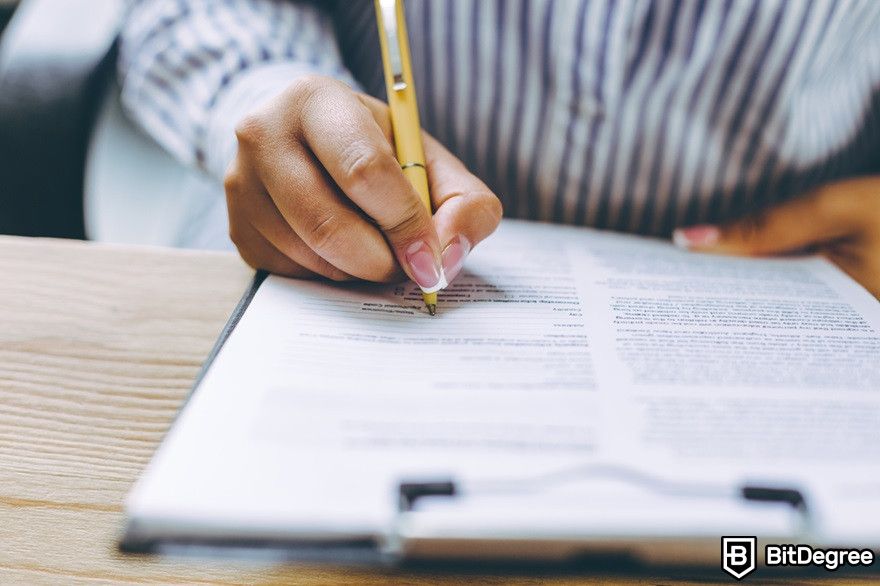 Thị trường gấu tiền điện tử: ảnh chụp cắt lớp bàn tay của một người phụ nữ đang ký hợp đồng.