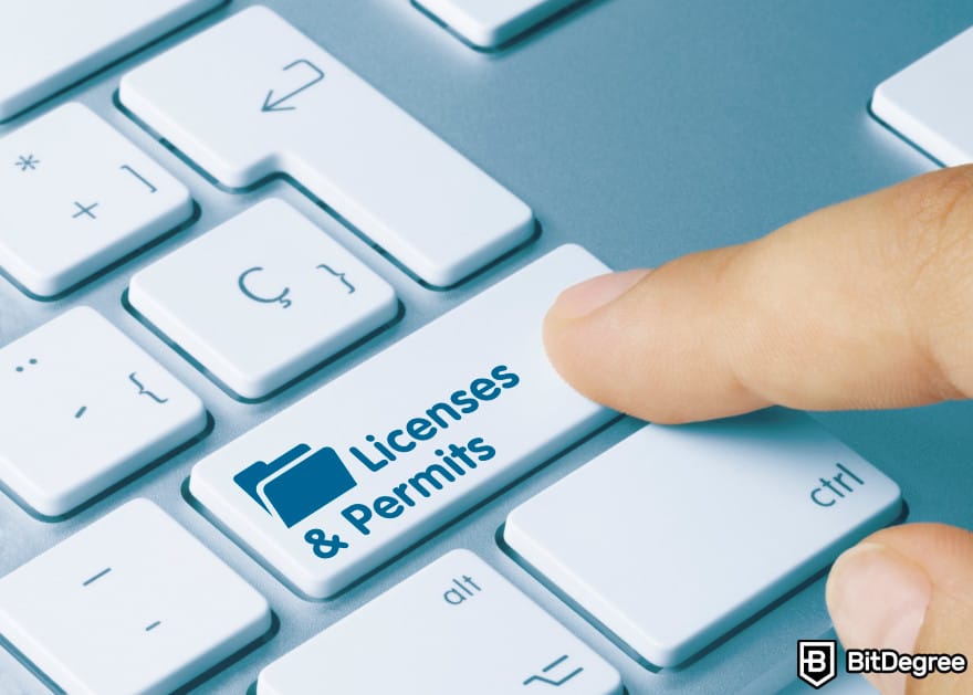 Como começar um negócio cripto: uma pessoa pressionando uma tecla do teclado que diz 'Licenças e permissões'.
