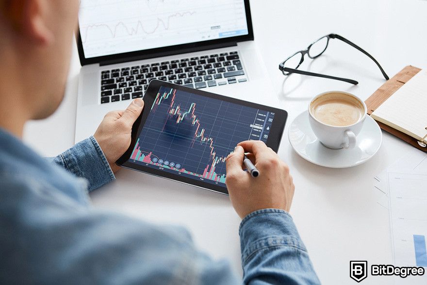 Notcoin Bybit: ada orang pegang tablet seluler yang menampilkan grafik harga.