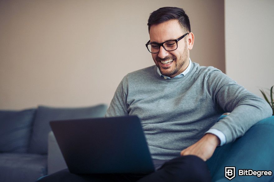 Bybit Nedir: Bir laptop kullanarak gülümseyen bir kişi.